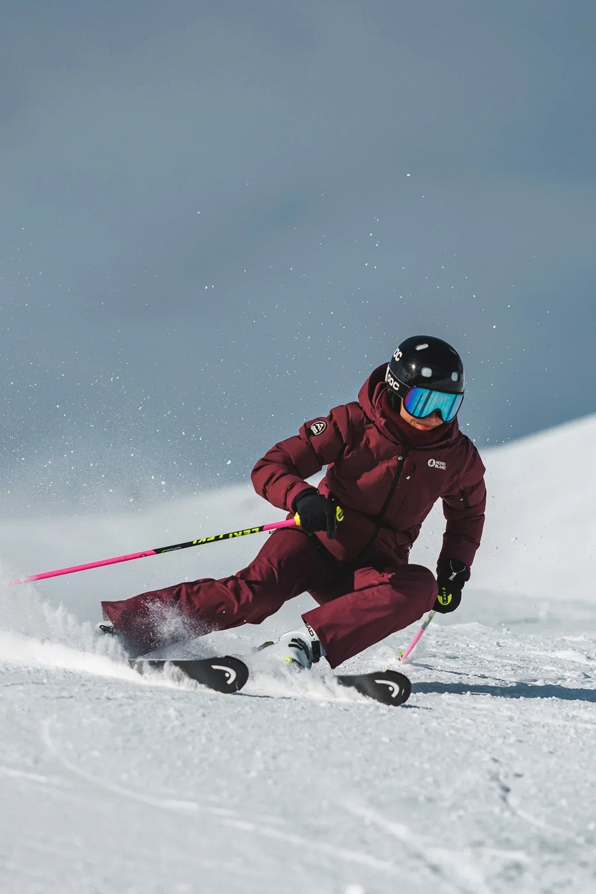 Female skier in a ski jacket and pants skiing down a slope