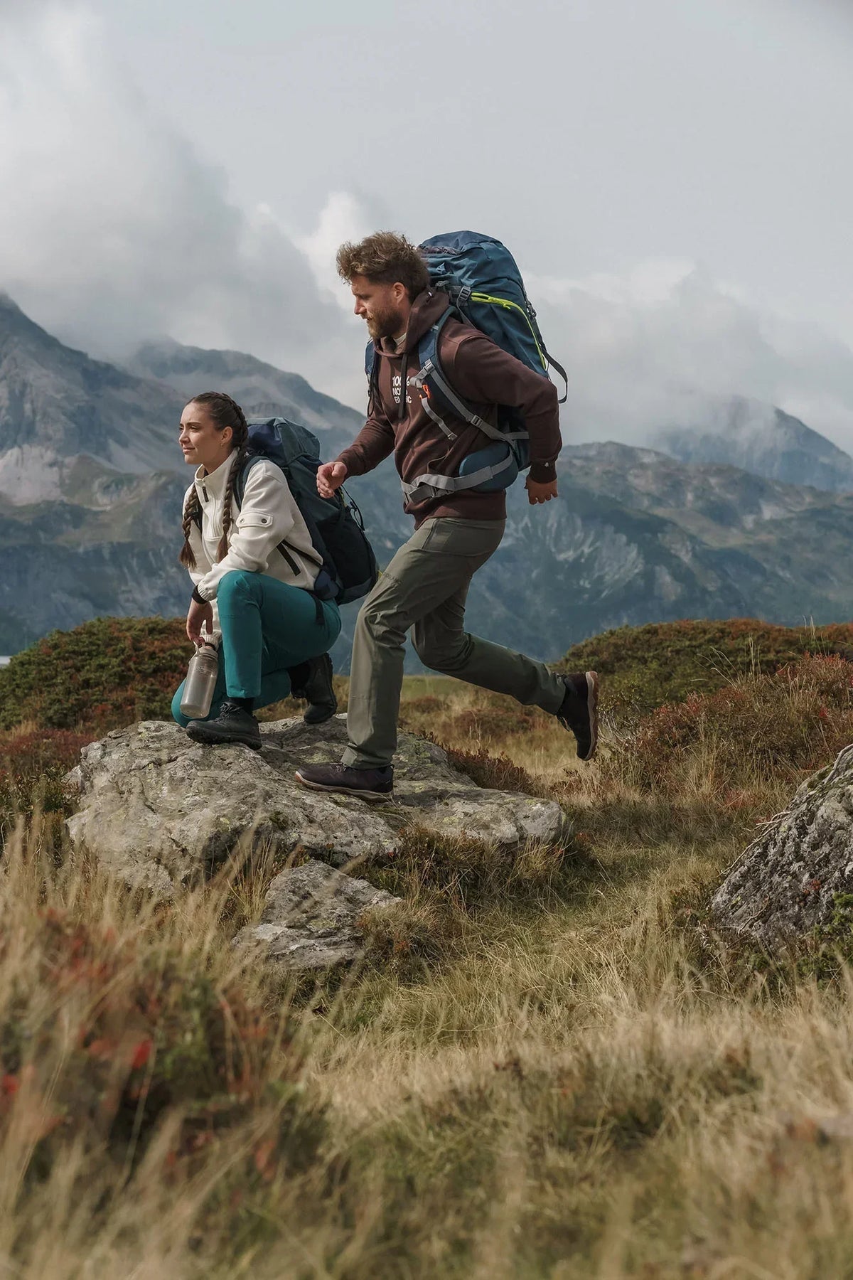 Two hikers with rucksacks in hiking trousers on a mountain ridge