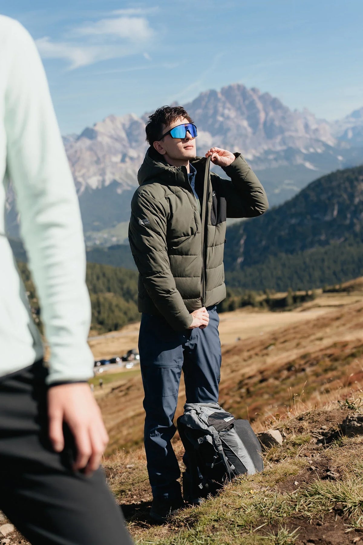 Man in a green winter jacket with a hood in the mountains